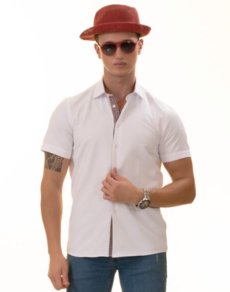 A man wearing a white paisley short sleeve shirt with a spread collar, paired with a red hat and sunglasses, standing against a white background.